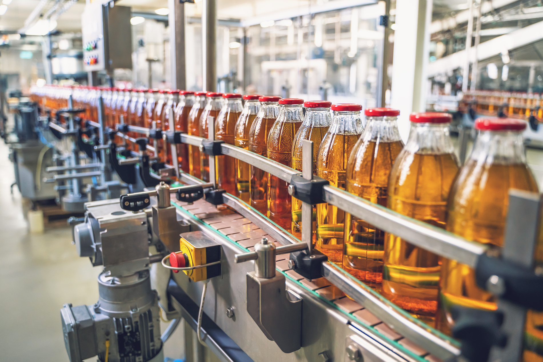 Conveyor belt, juice in glass bottles on beverage plant or factory interior, industrial manufacturing production line