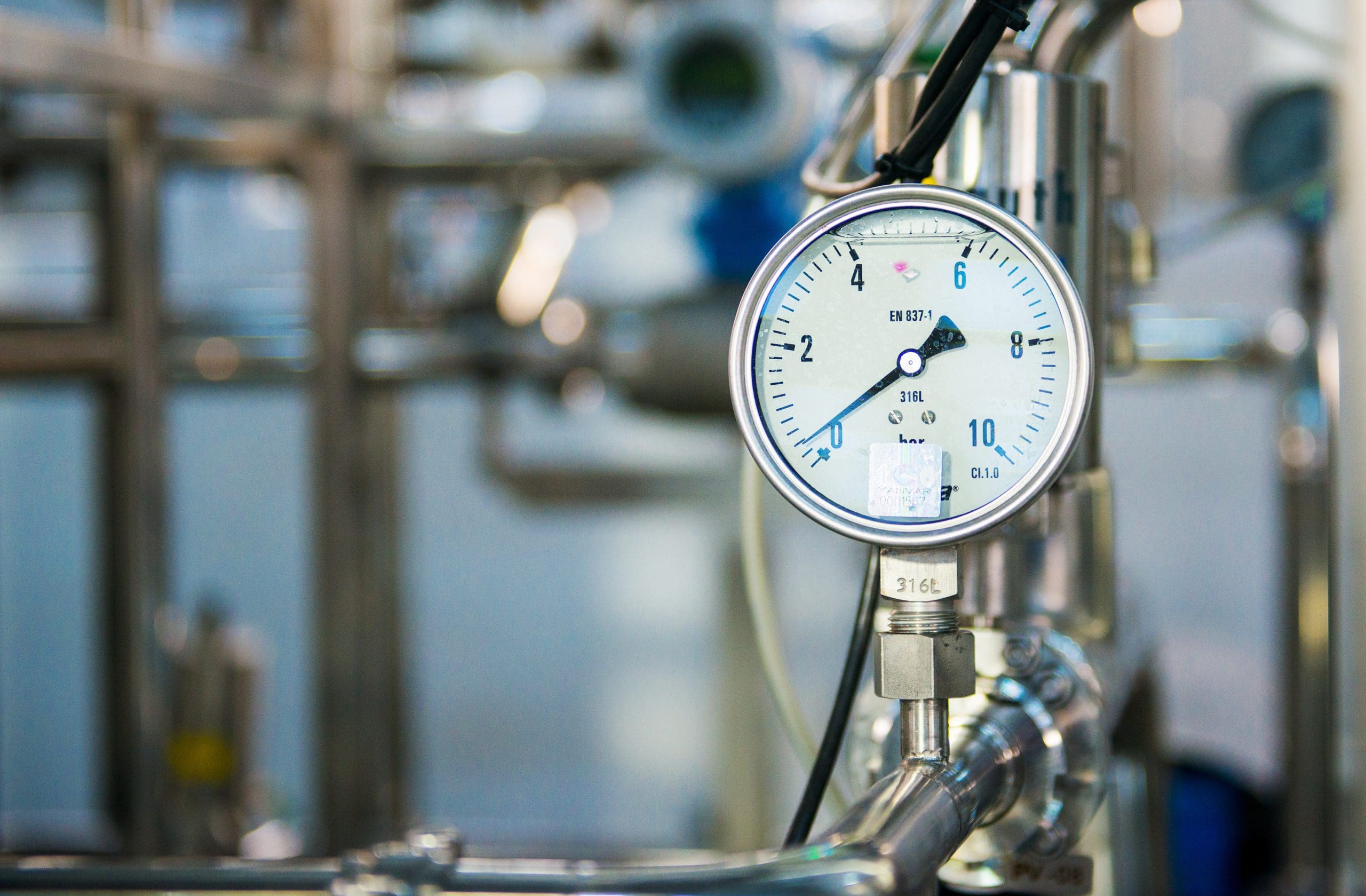 Industrial pressure meter – barometer and water pipes in the background